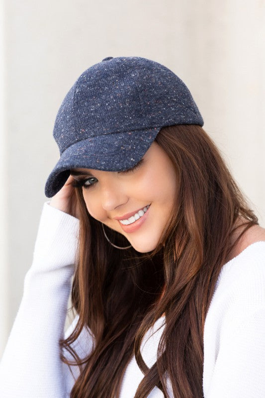 Woman smiling and wearing a Fall Tweed Ball Cap with an adjustable clasp and hoop earrings.