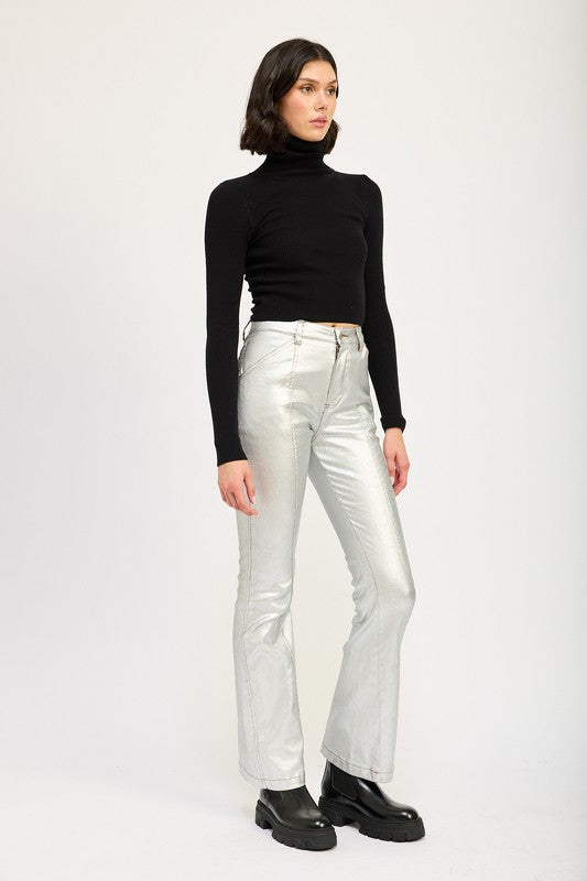 A size small model with short dark hair wearing black sunglasses, a TURTLE NECK LONG SLEEVE TOP in black, and metallic silver pants holds a small black handbag.