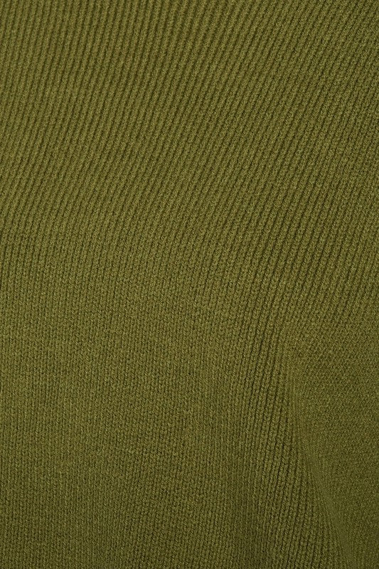 A woman wearing an OVER FITTED LONG SLEEVE SWEATER TOP made of 60% cotton in brown and khaki shorts holds a denim handbag with a brown strap against a neutral background.