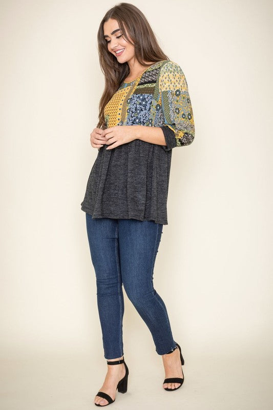 A woman with long dark hair poses against a plain background, wearing a 3/4 Sleeve Quilted Pattern Tunic which features a quilted design and a gray lower half.