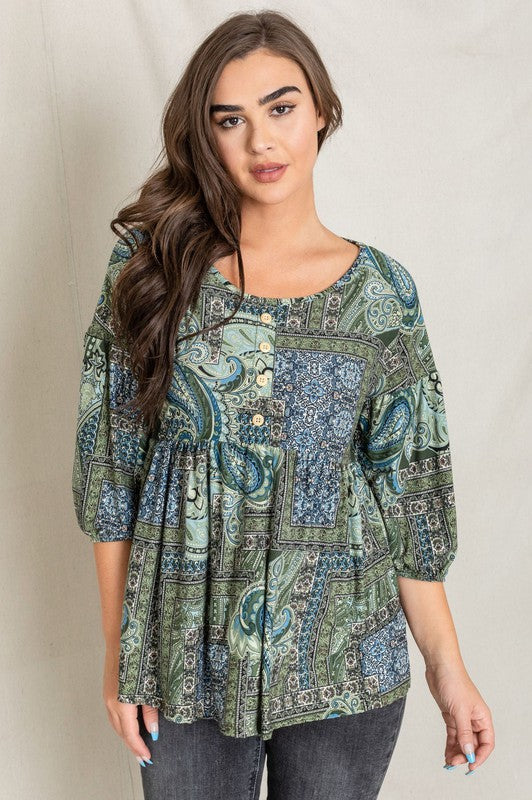 A woman with long brown hair wearing the Button Accent Paisley Top in green and blue, made from polyester, stands against a plain background.