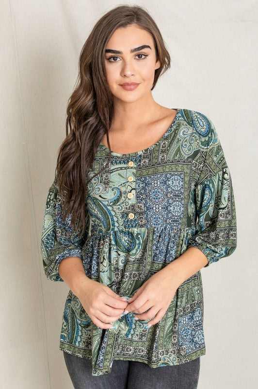 A woman with long brown hair wearing the Button Accent Paisley Top in green and blue, made from polyester, stands against a plain background.