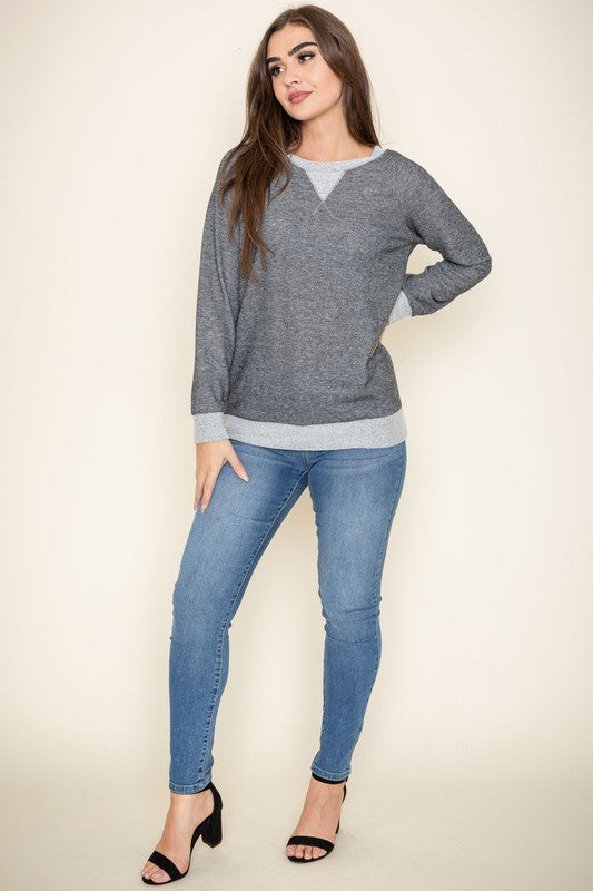 Modeling the Terry Crew Neck Tunic, characterized by its light-colored cuffs and neckline, a person poses against a plain background.