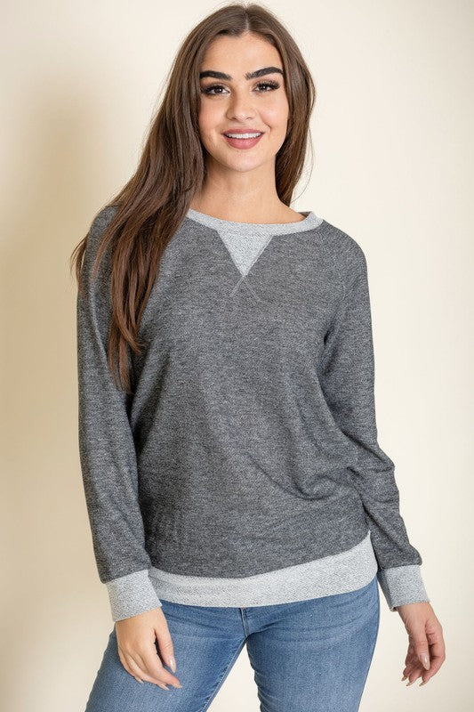 Modeling the Terry Crew Neck Tunic, characterized by its light-colored cuffs and neckline, a person poses against a plain background.