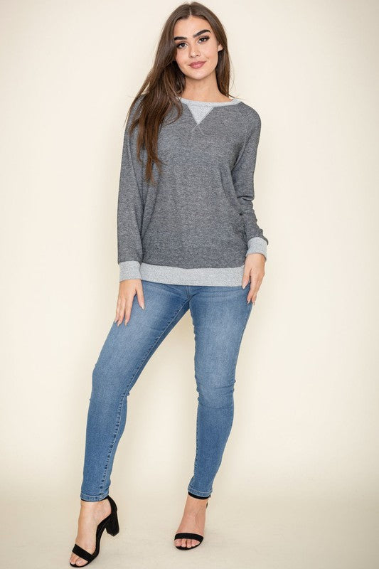 Modeling the Terry Crew Neck Tunic, characterized by its light-colored cuffs and neckline, a person poses against a plain background.