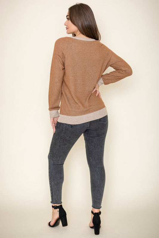 Modeling the Terry Crew Neck Tunic, characterized by its light-colored cuffs and neckline, a person poses against a plain background.