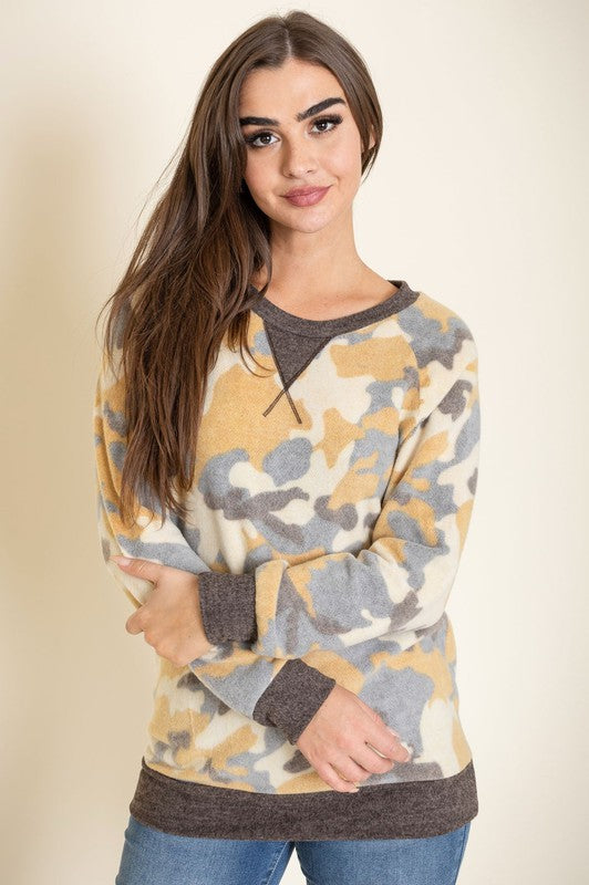 A woman with long hair is wearing a Camo Crew Neck Tunic, paired with dark jeans, and posing against a plain background. The tunic was made in the United States.