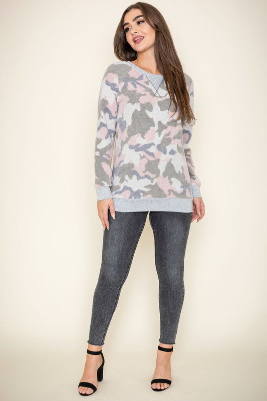 A woman with long hair is wearing a Camo Crew Neck Tunic, paired with dark jeans, and posing against a plain background. The tunic was made in the United States.