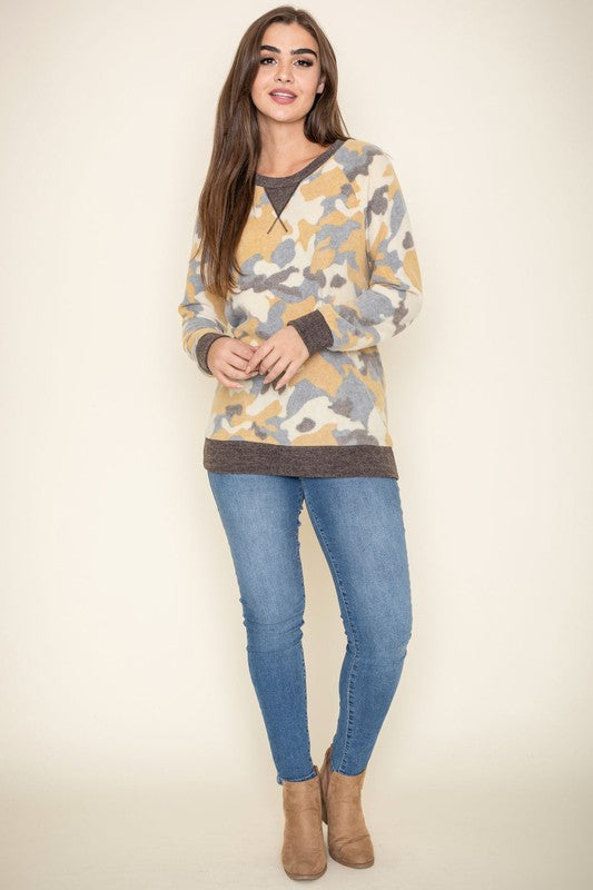 A person with long hair poses in a Plus Camo Crew Neck Tunic made of polyester spandex and jeans against a plain background.