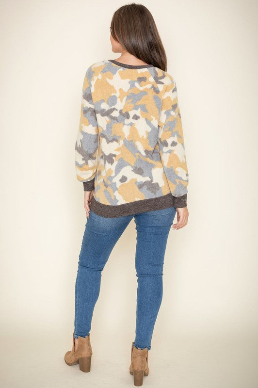 A woman with long hair is wearing a Camo Crew Neck Tunic, paired with dark jeans, and posing against a plain background. The tunic was made in the United States.