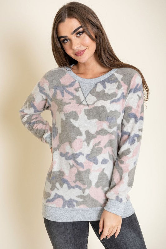 A woman with long hair is wearing a Camo Crew Neck Tunic, paired with dark jeans, and posing against a plain background. The tunic was made in the United States.