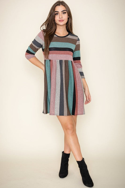 A woman is wearing the Multi Color Mini Dress, crafted from polyester spandex with long sleeves. She is looking off to the left. Made in the United States.