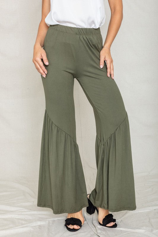 Person wearing Diagonal Trim Ruffle Hem Pants in olive green with a tiered design and black open-toe shoes, standing against an outdoor brick background.