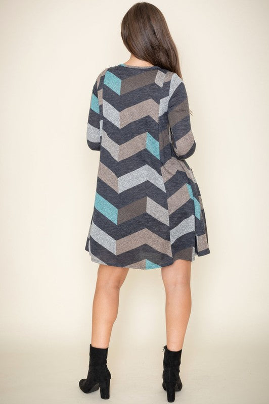 Against a plain backdrop, an individual elegantly poses in the Chevron A-Line Dress, featuring a polyester fabric and long sleeves.