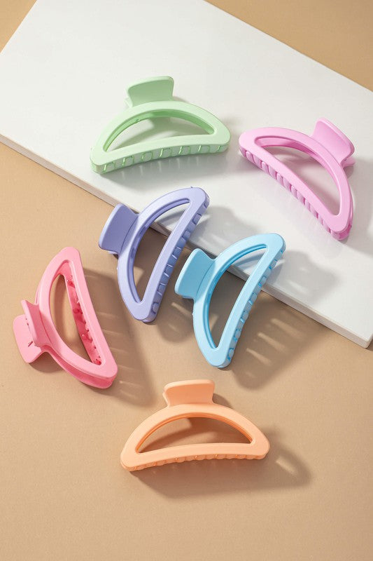 Five Iridescent Crescent Shape Big Claw Hair Clips, featuring the delicate tones of a Morandi color palette, are displayed on a beige surface with a white rectangular strip.