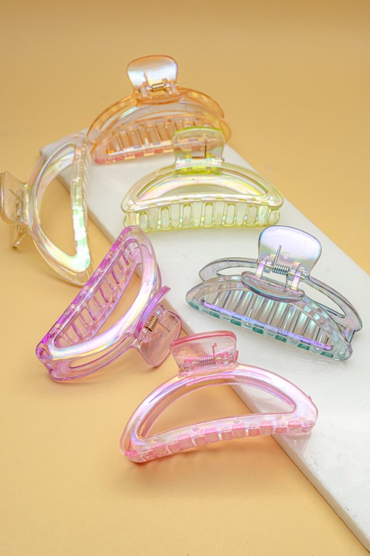 Five Iridescent Crescent Shape Big Claw Hair Clips, featuring the delicate tones of a Morandi color palette, are displayed on a beige surface with a white rectangular strip.