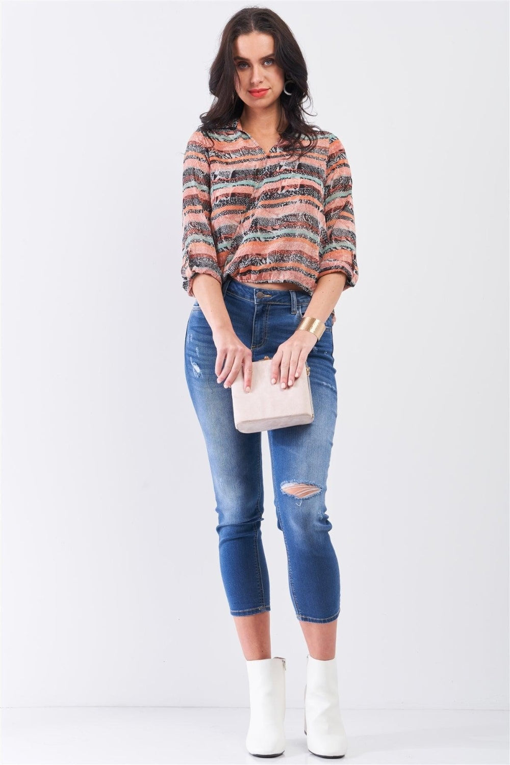 A woman with dark hair wears a Mono B Cutout Johnny Collar Three-Quarter Sleeve Blouse and distressed blue jeans, standing against a plain background.