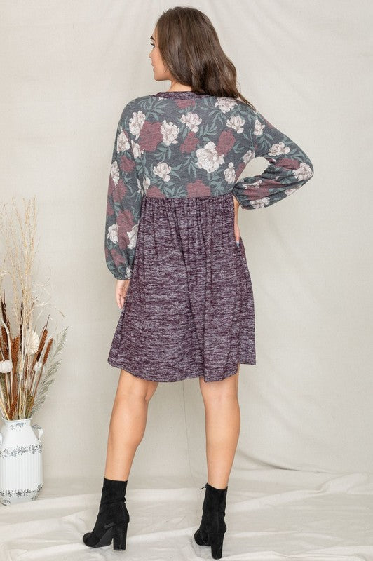 A woman wearing a Floral V Neck Boho Dress featuring floral patterned sleeves and standing against a neutral backdrop. Made in the United States, this outfit embodies timeless style and elegance.