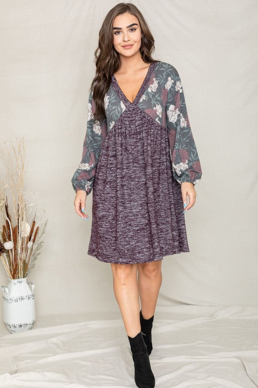 A woman wearing a Floral V Neck Boho Dress featuring floral patterned sleeves and standing against a neutral backdrop. Made in the United States, this outfit embodies timeless style and elegance.