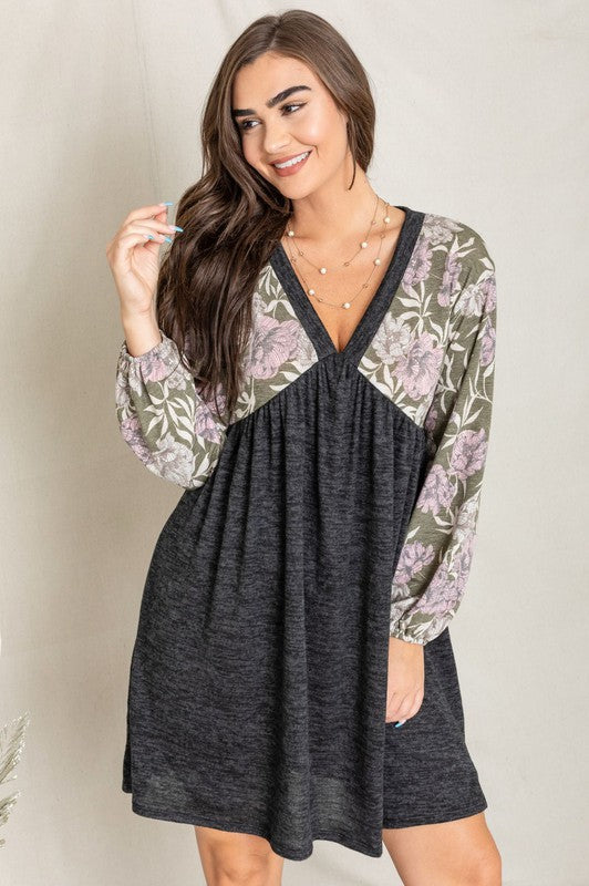 A woman wearing a Floral V Neck Boho Dress featuring floral patterned sleeves and standing against a neutral backdrop. Made in the United States, this outfit embodies timeless style and elegance.