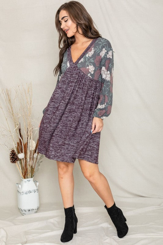 A woman wearing a Floral V Neck Boho Dress featuring floral patterned sleeves and standing against a neutral backdrop. Made in the United States, this outfit embodies timeless style and elegance.