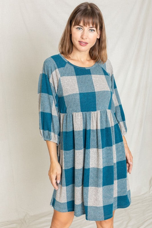 A person in a Checker Balloon Sleeve Midi Dress, featuring blue and gray checkered patterns and made of polyester, matched with tan ankle boots stands against a light background.