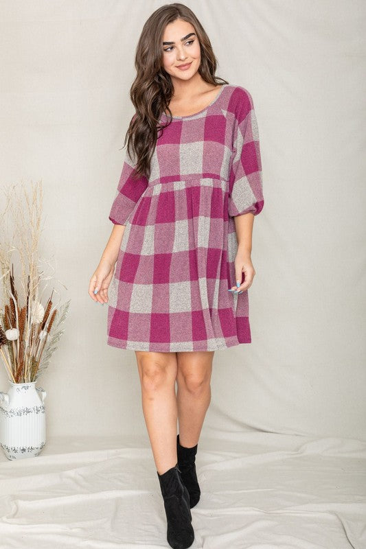 A person in a Checker Balloon Sleeve Midi Dress, featuring blue and gray checkered patterns and made of polyester, matched with tan ankle boots stands against a light background.