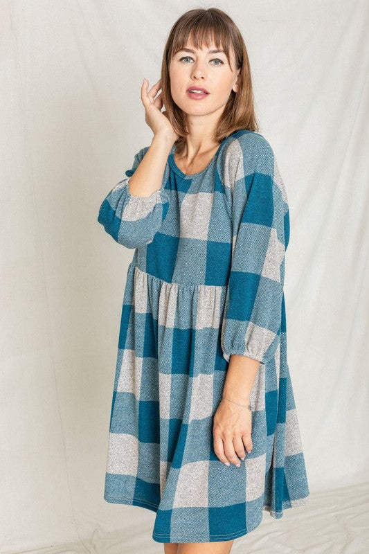 A person in a Checker Balloon Sleeve Midi Dress, featuring blue and gray checkered patterns and made of polyester, matched with tan ankle boots stands against a light background.