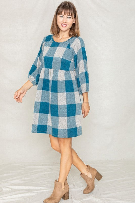 A person in a Checker Balloon Sleeve Midi Dress, featuring blue and gray checkered patterns and made of polyester, matched with tan ankle boots stands against a light background.