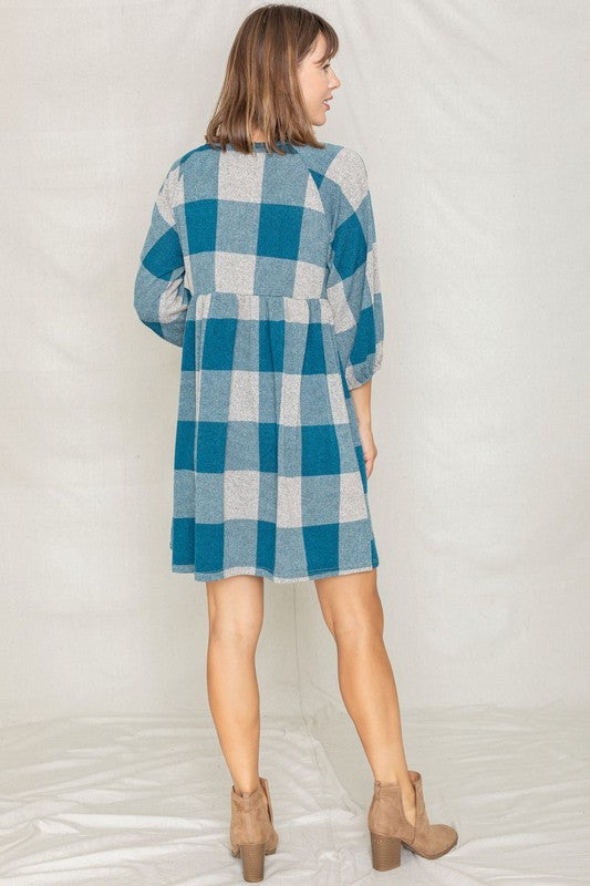 A person in a Checker Balloon Sleeve Midi Dress, featuring blue and gray checkered patterns and made of polyester, matched with tan ankle boots stands against a light background.