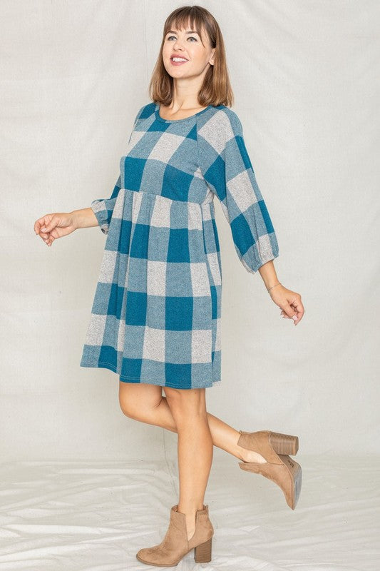 A person in a Checker Balloon Sleeve Midi Dress, featuring blue and gray checkered patterns and made of polyester, matched with tan ankle boots stands against a light background.