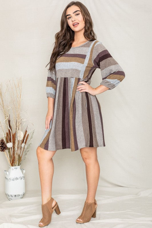 A person stands smiling, dressed in a Mix Stripe Balloon Sleeve Midi Dress that features multi-colored horizontal stripes in shades of blue, brown, and gray. The midi dress, crafted from polyester, includes three-quarter sleeves and handy pockets.