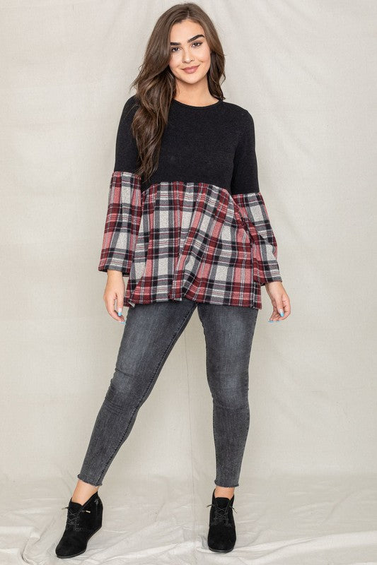 A person wearing the Bell Sleeve Plaid Tunic in gray polyester, featuring yellow plaid flares at the sleeves and bottom hem, is standing against a neutral background.