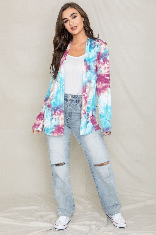 A woman poses for a picture, highlighting her stylish Tie Dye Elbow Patch Open Cardigan. The vibrant colors and unique design emphasize the craftsmanship of this piece, proudly made in the United States.