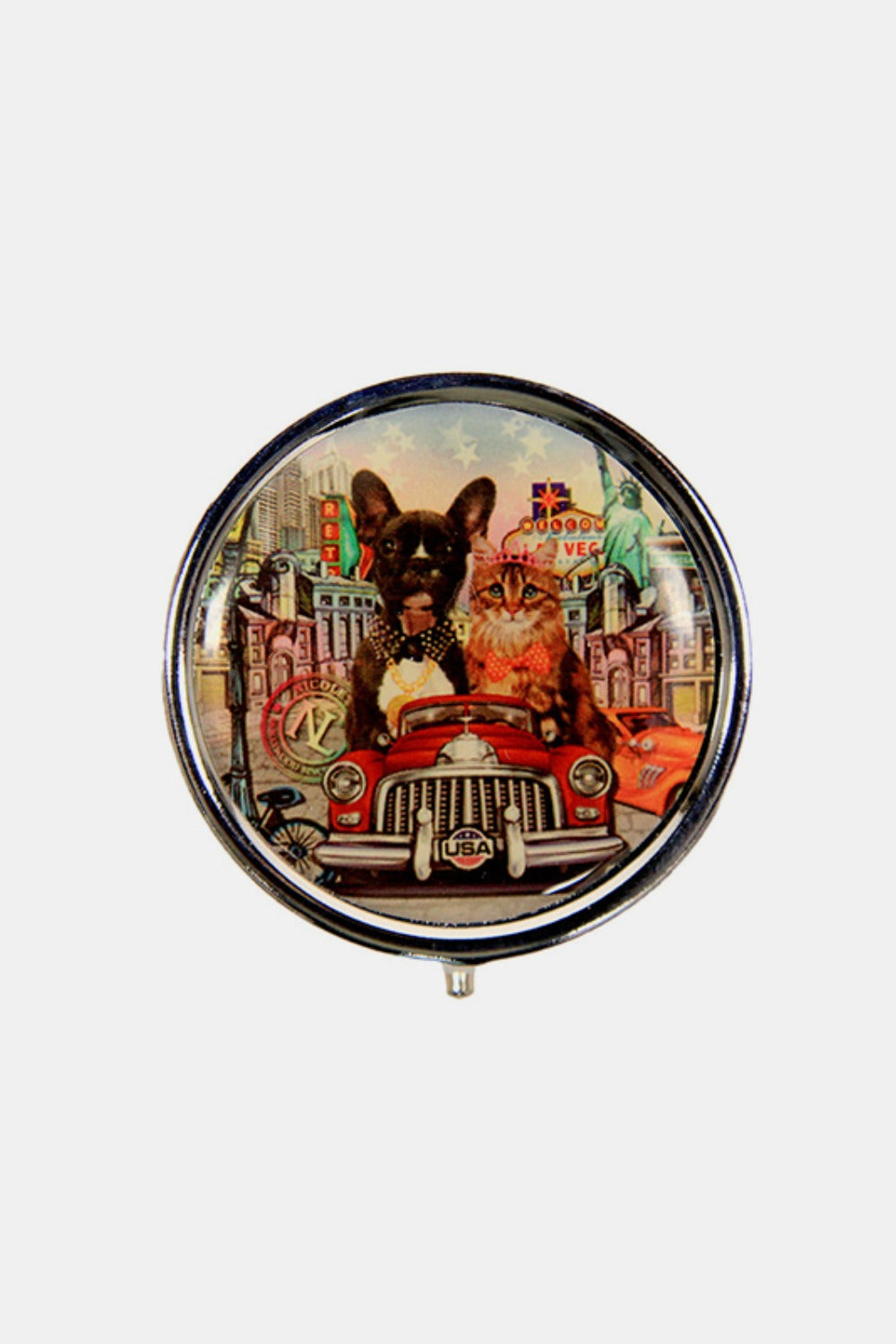 The Nicole Lee USA Print Metallic Circular Small Pill Case holds a metal pin that showcases an illustration of a dog and cat driving a red convertible through a city adorned with iconic buildings and landmarks, all wrapped in a sleek silver-tone metal exterior.