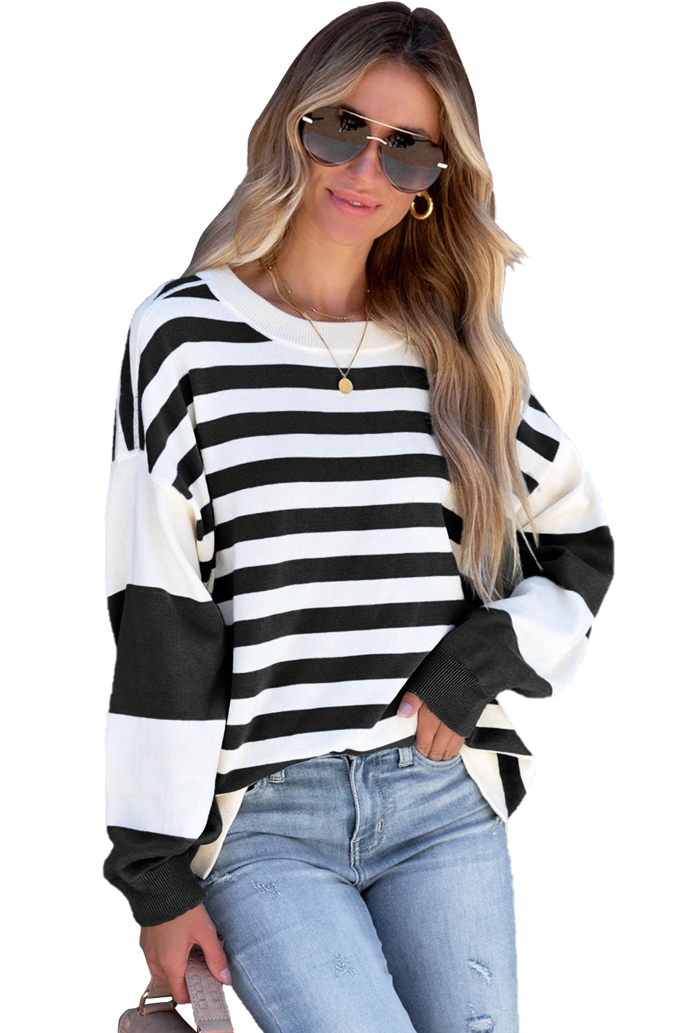 A person stands against a gray background, wearing sunglasses, a relaxed-fit Black Stripe Drop Shoulder Striped Pullover Sweatshirt, and ripped blue jeans, with long, wavy blonde hair.