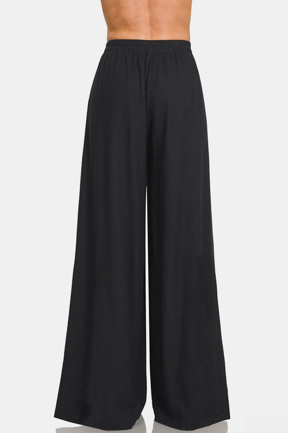 A person wearing Zenana Pleated Linen Blend Wide Leg Pants with an elastic waistband. The chic addition of these wide-leg silhouette pants is evident, even though the image is cropped at the torso and feet.