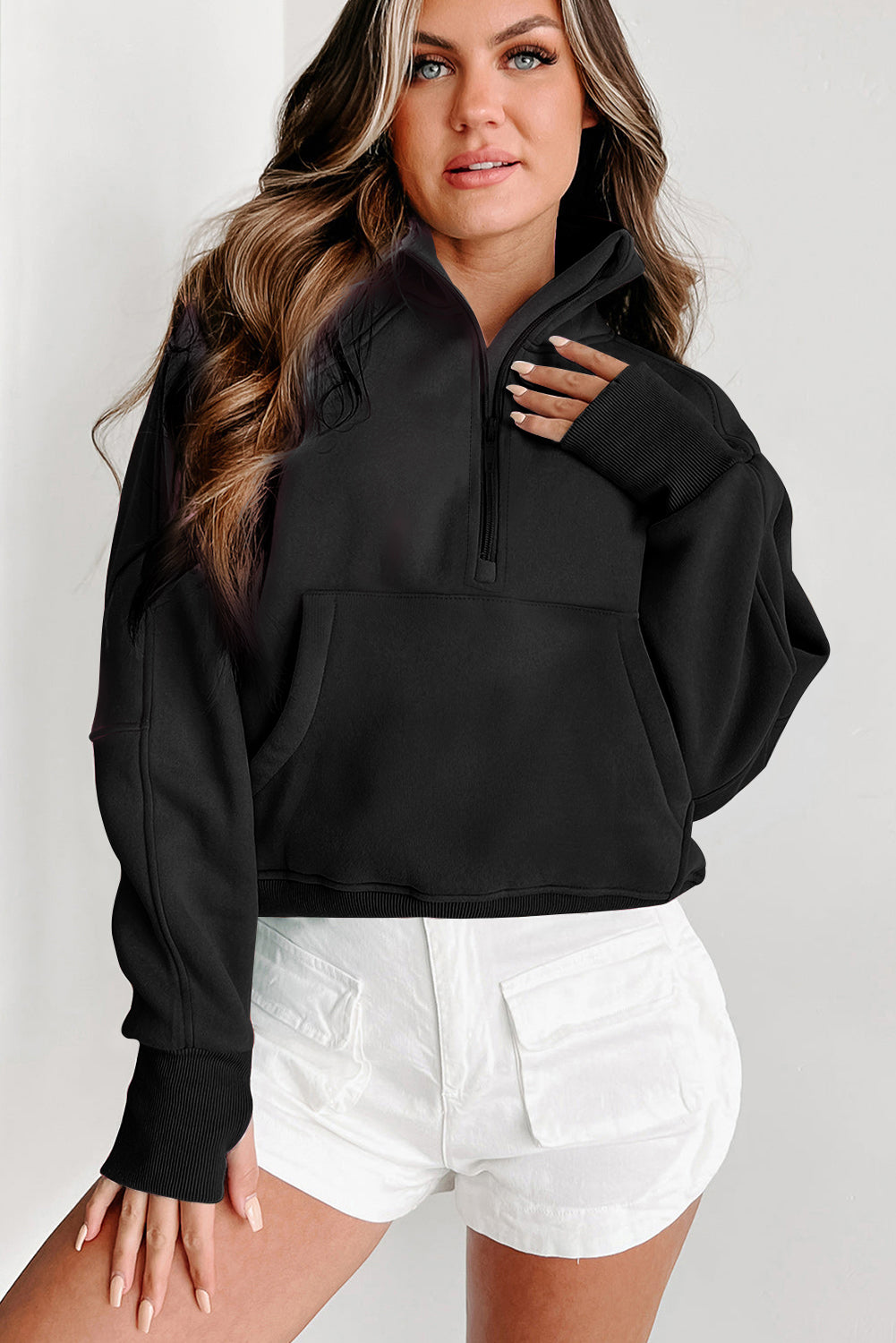 A person with long, wavy hair wearing a chic Black Fleece Lined Zip Up Stand Collar Thumbhole Sleeve Sweatshirt and white shorts stands facing away from the camera, showcasing a trendy, comfy design perfect for casual outings.