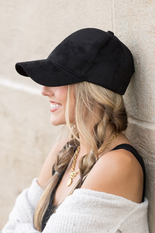 Woman smiling and leaning against a wall while wearing a Suede Boyfriend Ball Cap Hat.