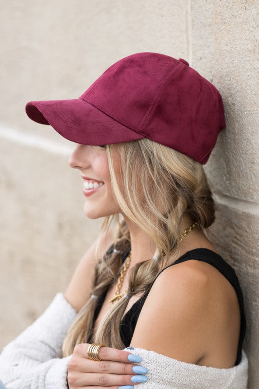Woman smiling and leaning against a wall while wearing a Suede Boyfriend Ball Cap Hat.