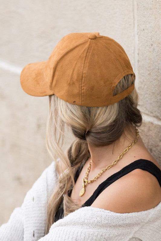 Woman smiling and leaning against a wall while wearing a Suede Boyfriend Ball Cap Hat.