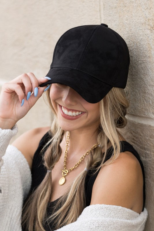 Woman smiling and leaning against a wall while wearing a Suede Boyfriend Ball Cap Hat.