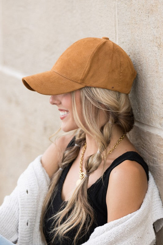 Woman smiling and leaning against a wall while wearing a Suede Boyfriend Ball Cap Hat.