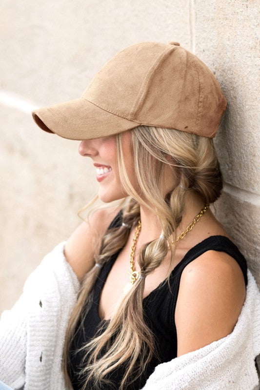 Woman smiling and leaning against a wall while wearing a Suede Boyfriend Ball Cap Hat.