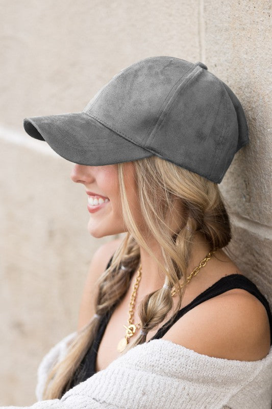Woman smiling and leaning against a wall while wearing a Suede Boyfriend Ball Cap Hat.
