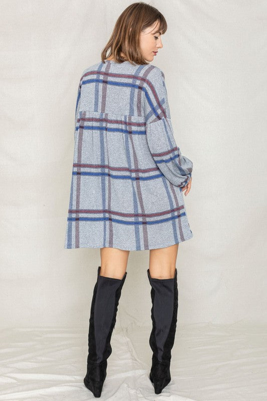 A woman in a Plaid Empire Waist Balloon Sleeve Mini Dress smiles and poses in front of a plain backdrop.