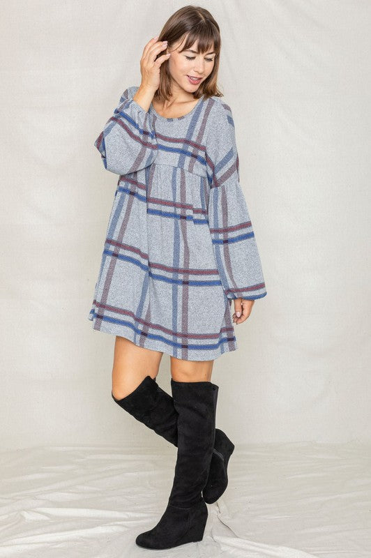 A woman in a Plaid Empire Waist Balloon Sleeve Mini Dress smiles and poses in front of a plain backdrop.