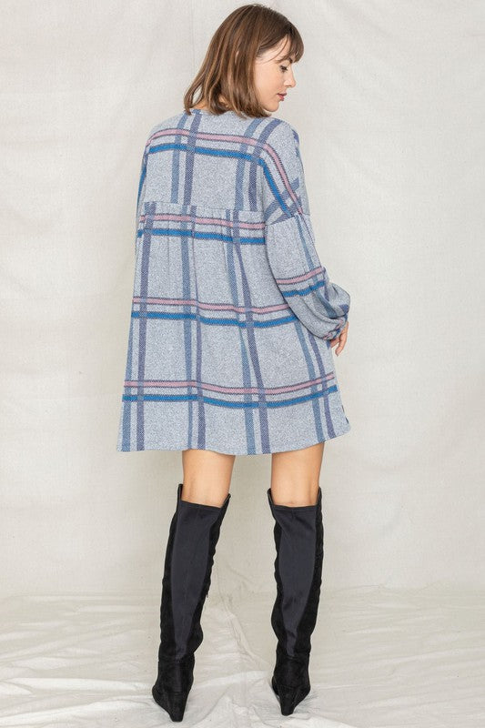 A woman wearing a Plaid Empire Waist Balloon Sleeve Mini Dress stands and smiles against a plain background.