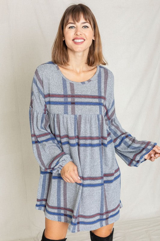 A woman in a Plaid Empire Waist Balloon Sleeve Mini Dress smiles and poses in front of a plain backdrop.