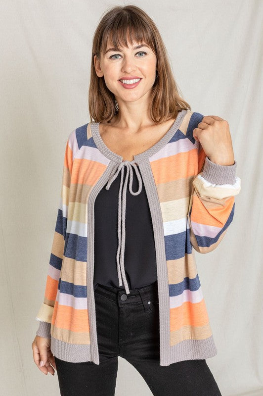 A person wearing the Multi Color Stripe Waffle Trim Open Cardigan over a green top and black pants stands against a light background.